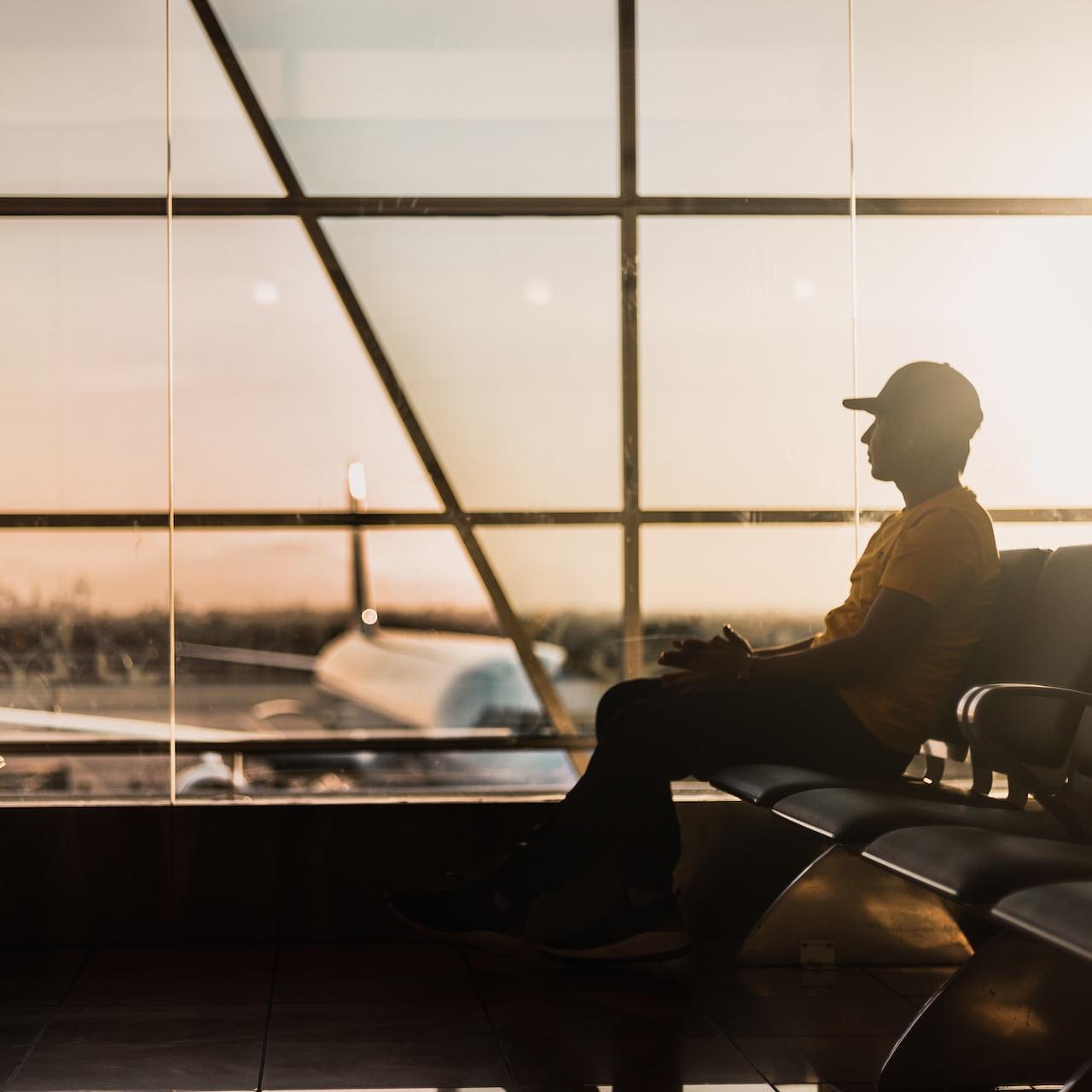 man sitting on gang chair near window