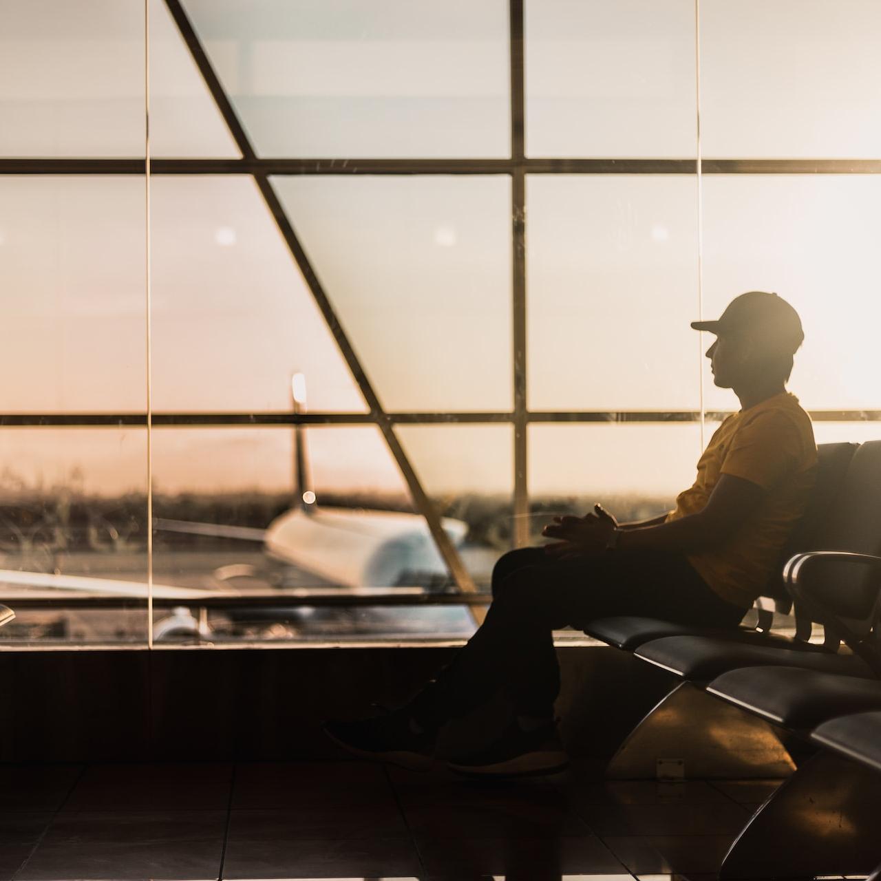 man sitting on gang chair near window